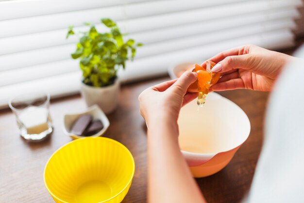 Crop woman pouring egg into bowl