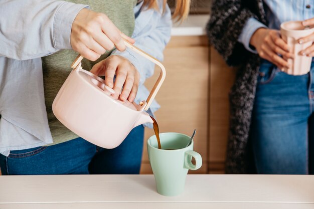 キッチンに茶を注いで栽培する女性