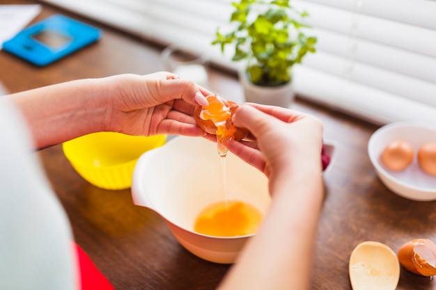 Crop woman pouring yolk into bowl