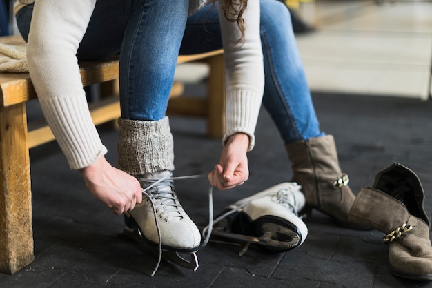 Crop woman putting on ice skates