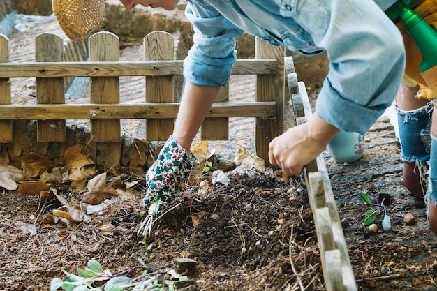 Crop woman raking soil