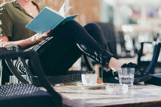 Crop woman reading book near low table