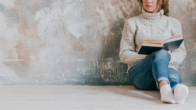 壁の近くで作物の女性の読書