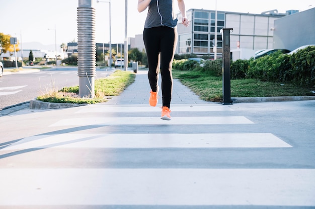 Crop woman running on crosswalk