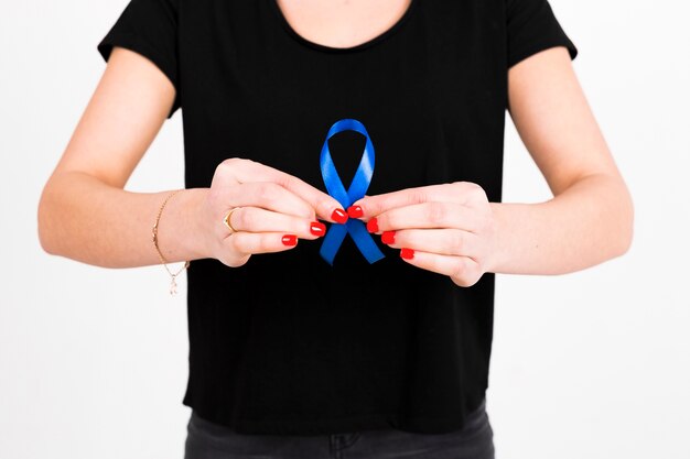 Crop woman showing blue ribbon