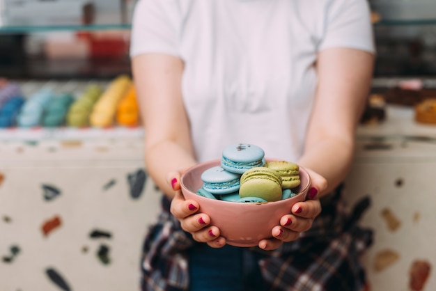 Crop woman showing bowl with macaroons