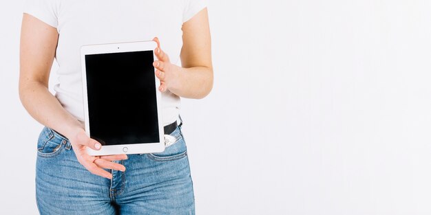 Crop woman showing tablet