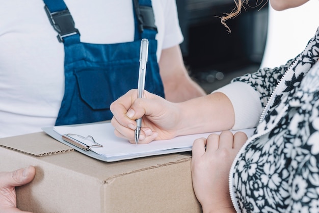 Free photo crop woman signing on clipboard for parcel