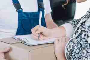 Foto gratuita la donna del raccolto che firma sugli appunti per il pacchetto