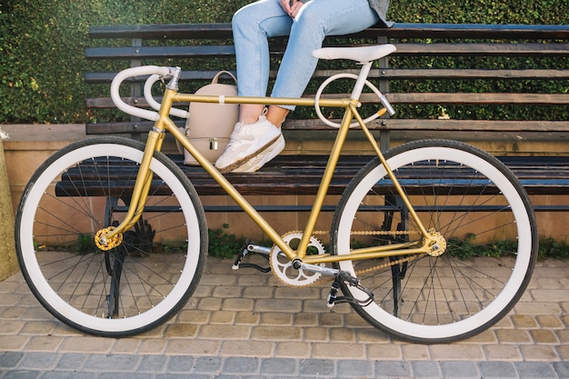 Foto gratuita raccolga la donna che si siede sul banco dietro la bicicletta