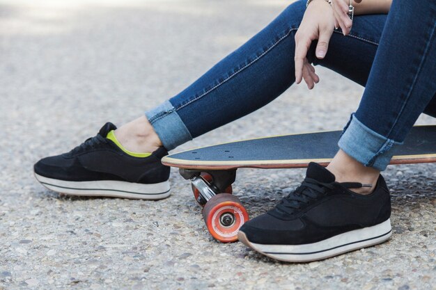 Crop woman sitting on longboard