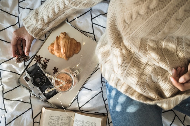 Free photo crop woman sitting near camera and breakfast food