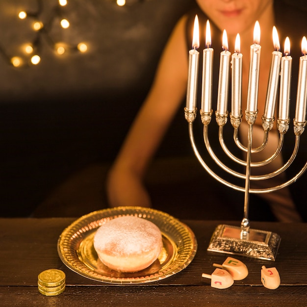 Crop woman sitting near Hanukkah symbols