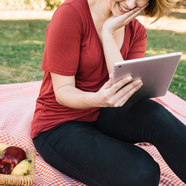 Crop woman smiling and using tablet