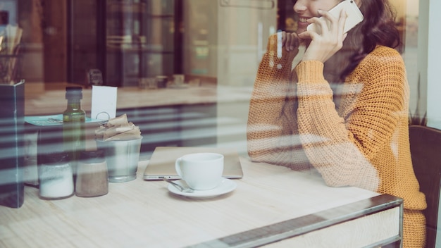 Foto gratuita ritaglia la donna che parla sul telefono nella caffetteria