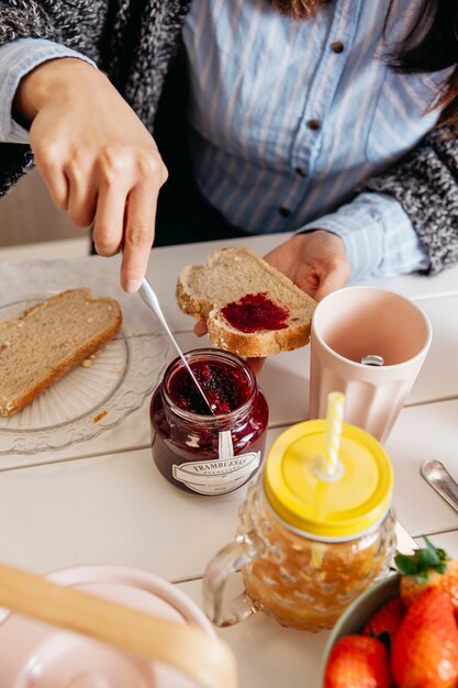 Crop woman spreading jam on bread