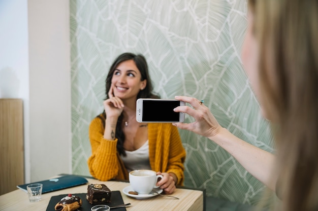 Crop woman taking picture of friend