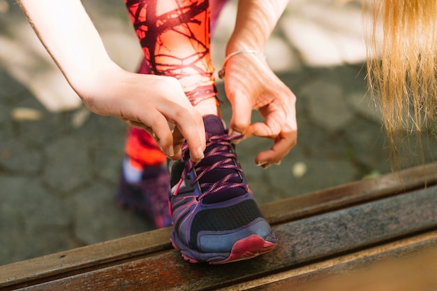 Foto gratuita ritaglia la donna che lega i lacci con le scarpe da ginnastica