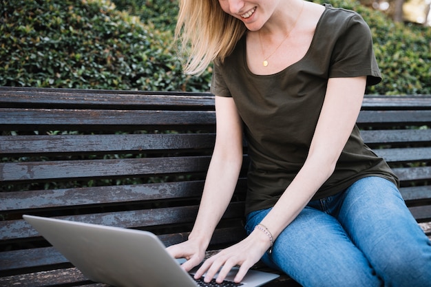 Crop woman using laptop and smiling