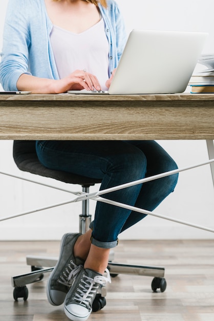 Foto gratuita raccolga la donna che per mezzo del computer portatile alla tavola