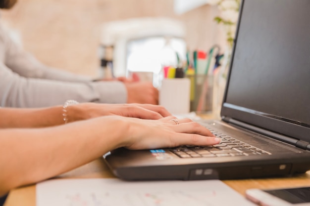 Crop woman using laptop