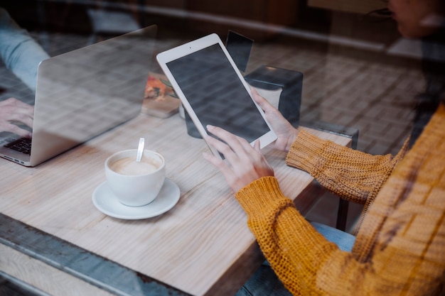 Raccolga la donna che utilizza la compressa che si siede nel caffè