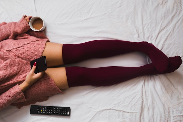 Free photo crop woman with coffee and smartphone