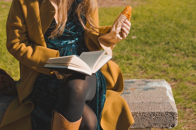 Foto gratuita raccolga la donna con il libro di lettura del croissant