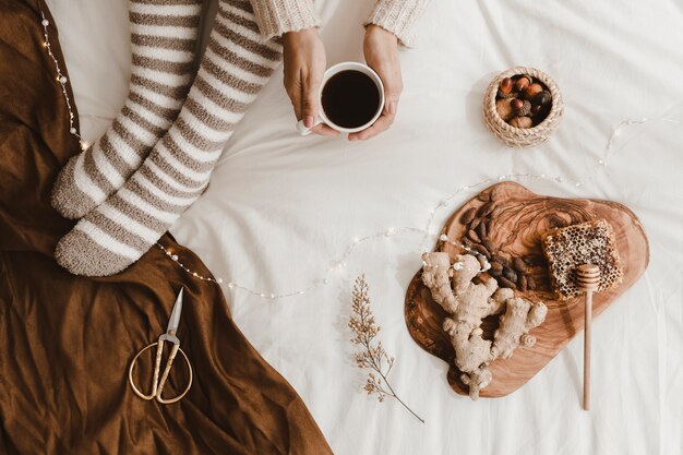 Crop woman with drink near snacks and scissors