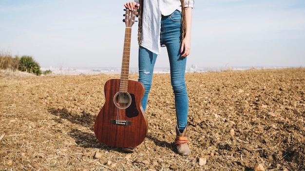 Foto gratuita ritaglia la donna con la chitarra nel campo