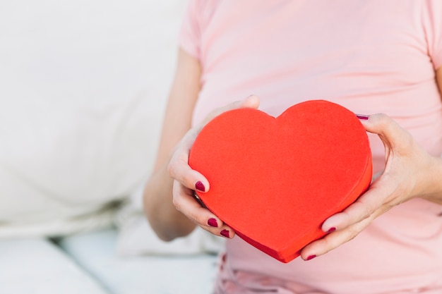 Crop woman with heart-shaped box