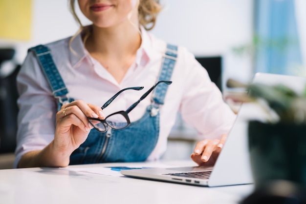 Crop woman with laptop and glasses