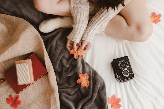 Crop woman with leaf near camera and gifts