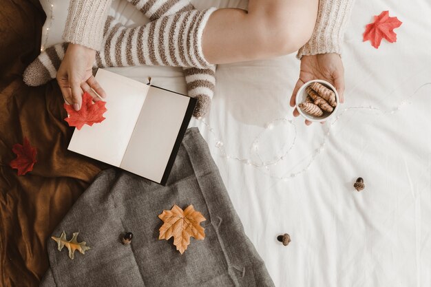 Crop woman with leaves and ginger near book