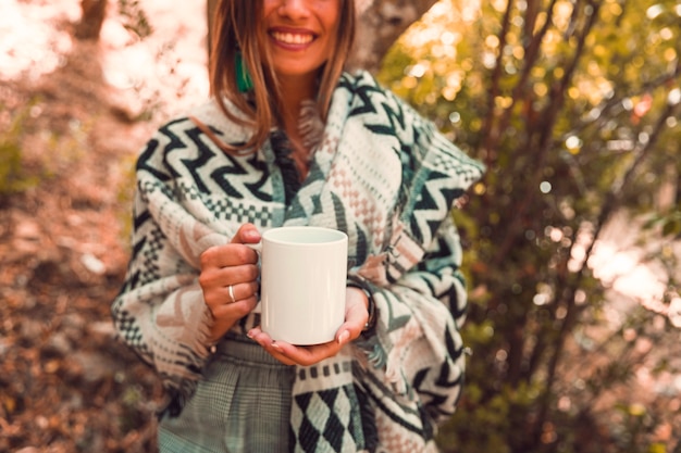 Raccolga la donna con la tazza in foresta