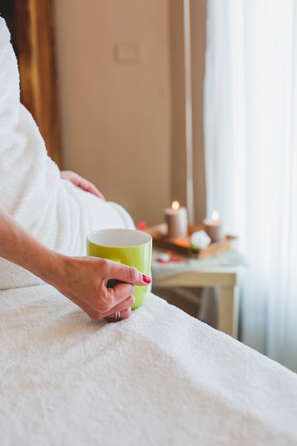 Crop woman with mug in spa salon