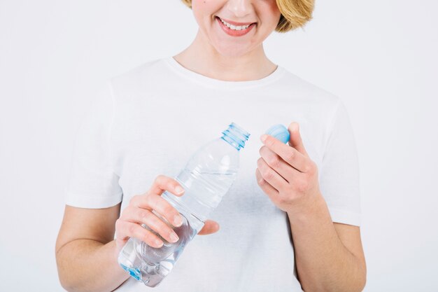 Crop woman with opened bottle on white