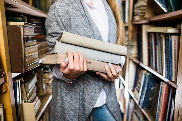 Crop woman with pile of books