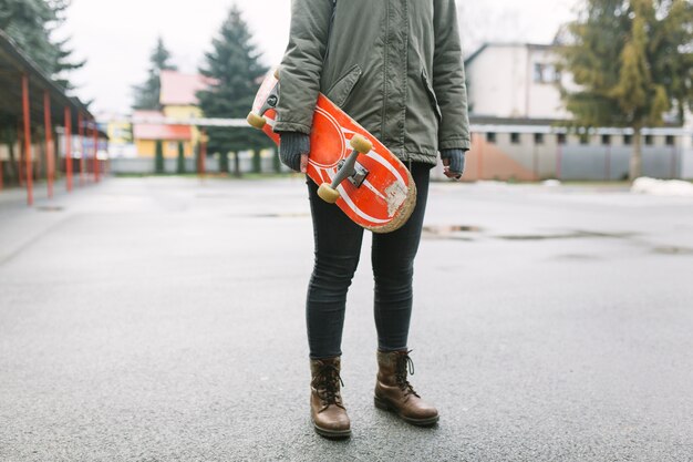 Crop woman with skateboard in park