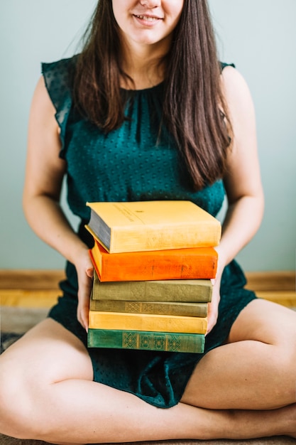 Crop woman with stack of old books