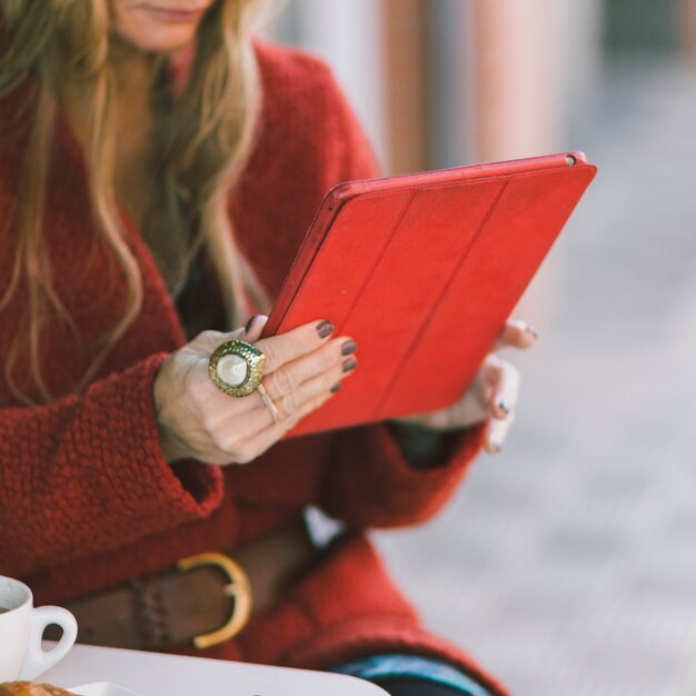 Crop woman with tablet in red cover