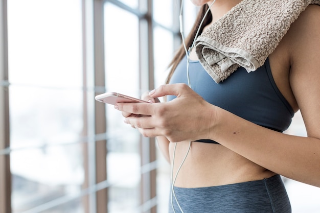 Ritaglia la donna con asciugamano e smartphone