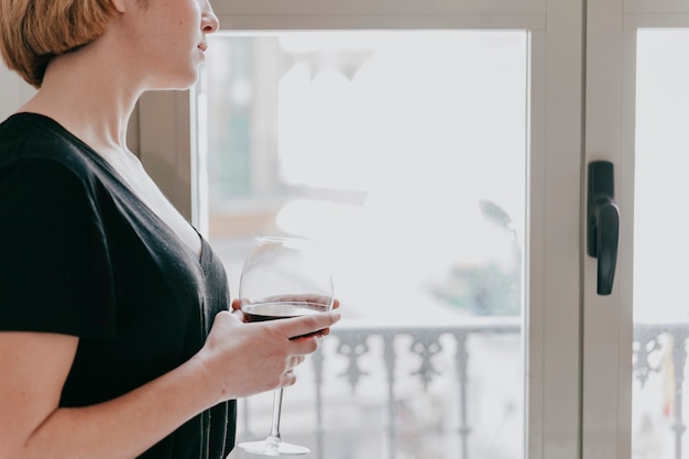 Free photo crop woman with wine at window