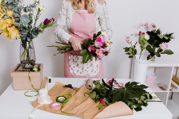 Crop woman working with flowers and paper