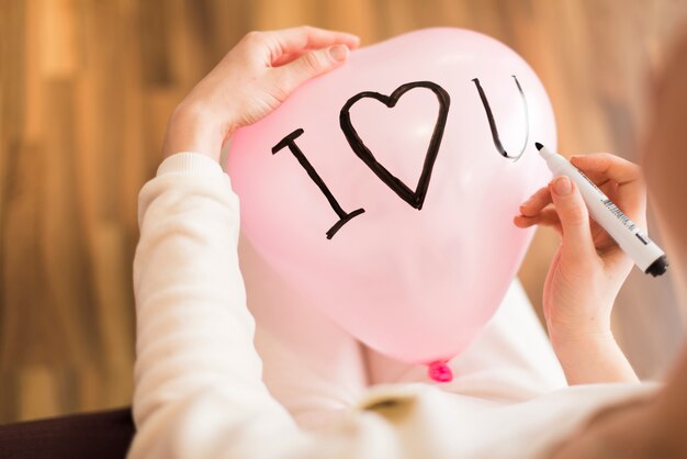 Crop woman writing on balloon