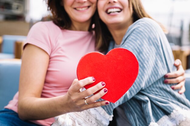 Crop women showing heart shaped box