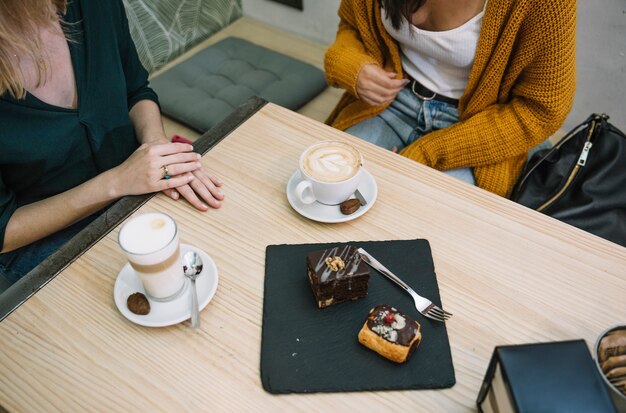 Crop women sitting in cafe