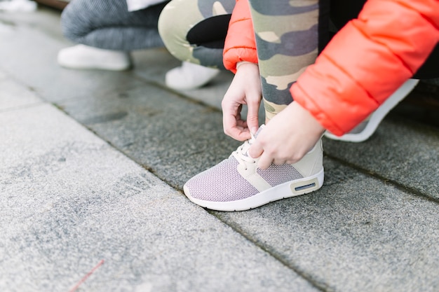 Crop women tying laces on sneakers