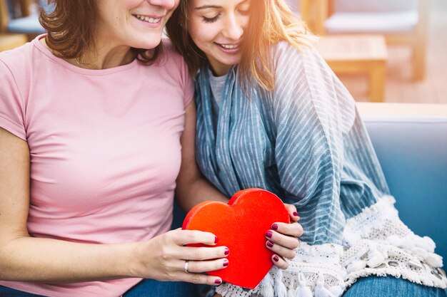 Crop women with heart-shaped box