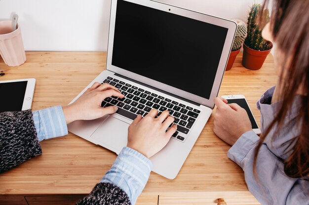 Crop women working at laptop